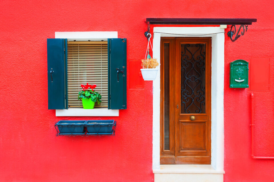 Door and window with flower on the red facade of the house