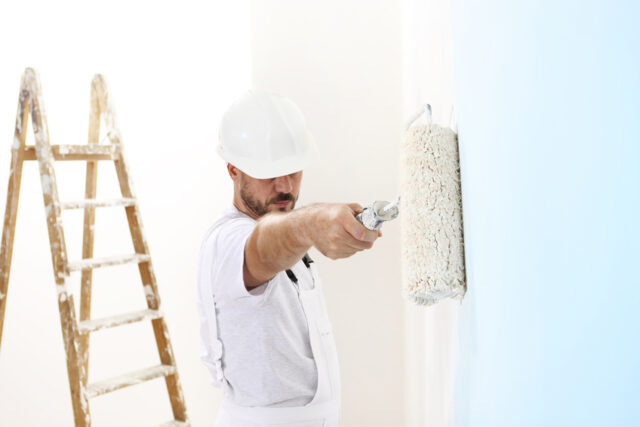 painter man at work with a paint roller on the wall